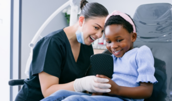 Dental assistant and patient smiling at the dentist together.