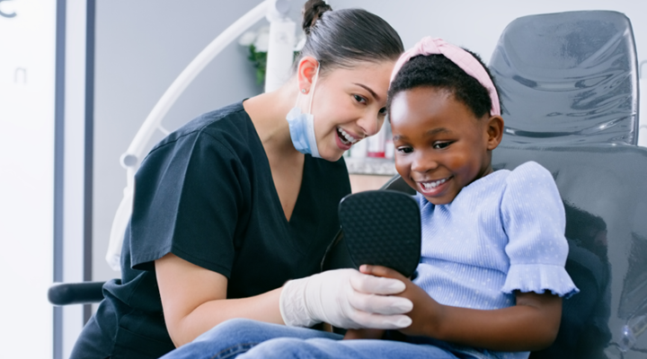 Dental assistant and patient smiling at the dentist together.