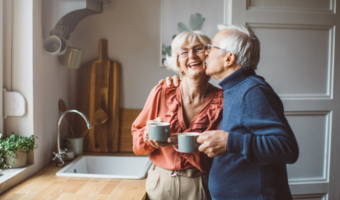 Older adult couple smiling and drinking coffee.