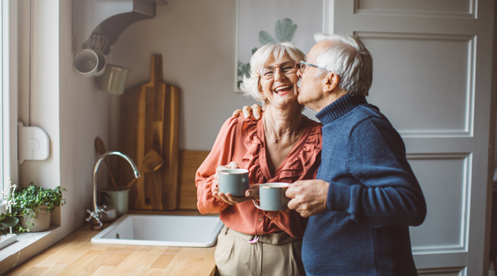 Older adult couple smiling and drinking coffee.