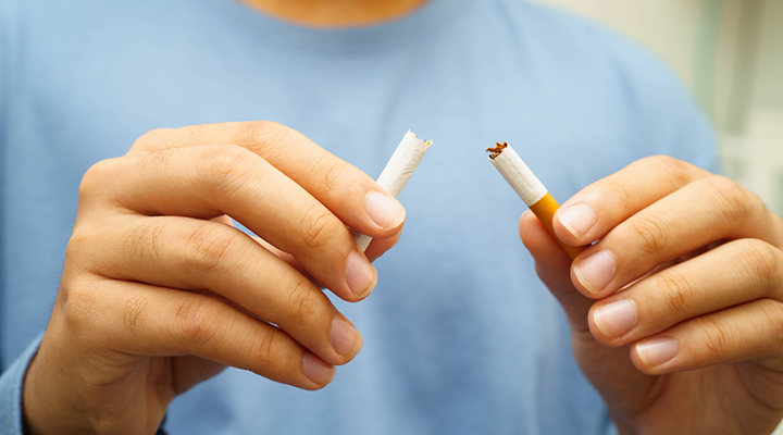 Person breaking a cigarette in half.