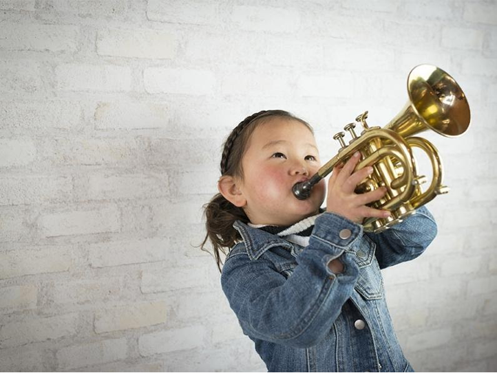 A young girl plays a horn instrument.
