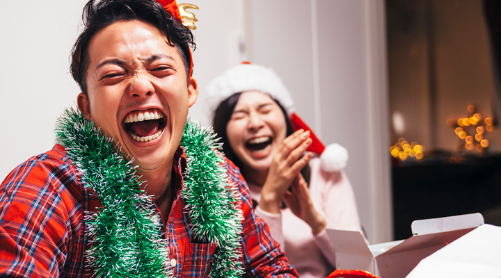 Two people smiling and laughing, while wearing holiday clothes.