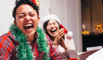 Two people smiling and laughing, while wearing holiday clothes.