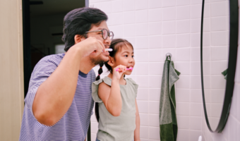 Father and daughter brushing their teeth.