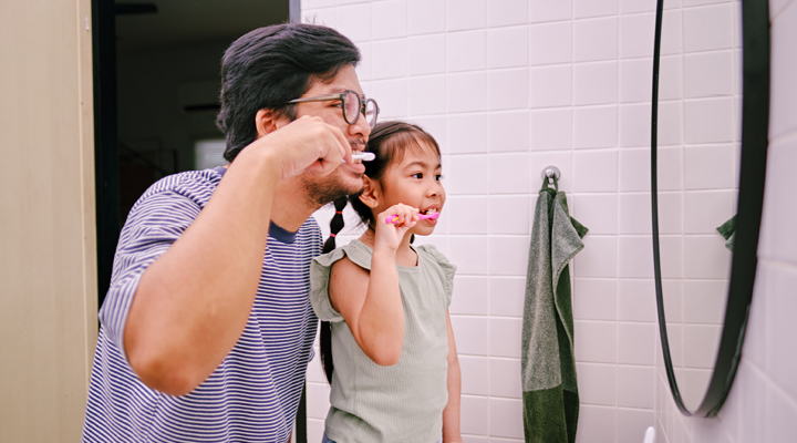 Father and daughter brushing their teeth.