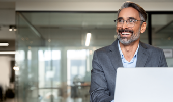Person smiling and working on a computer in the office.