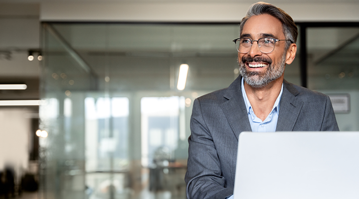 Person smiling and working on a computer in the office.