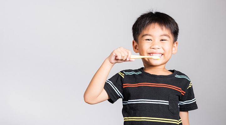 Child smiling and brushing his teeth.