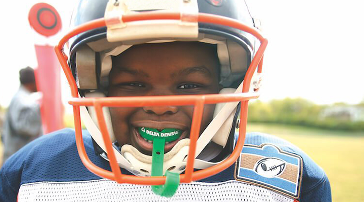 Kid wearing a delta dental mouthguard in football gear.