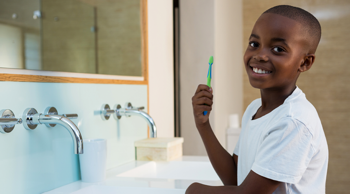 Child smiling and brushing their teeth.