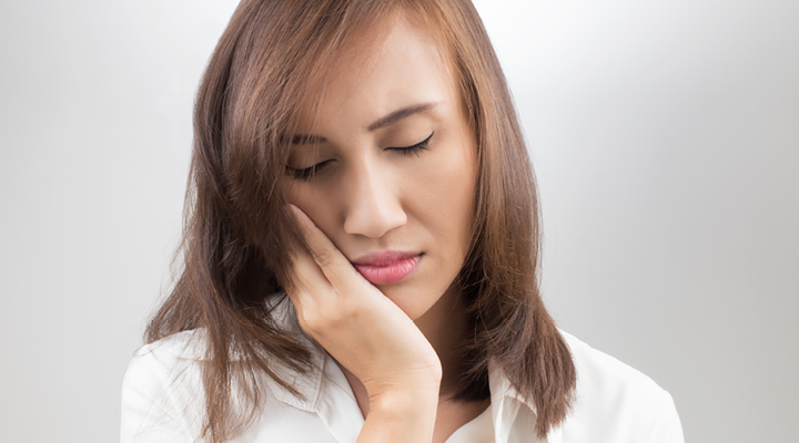 Person holding their mouth in pain.