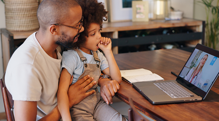 Father and son talking to their dentist on the computer.