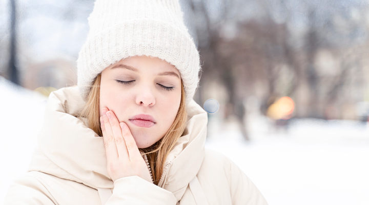 Person in the snow, holding their jaw in pain.