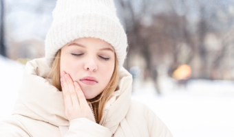 Person in the snow, holding their jaw in pain.