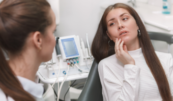 Person holding their jaw in pain at the dentist.