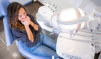 Person covering their mouth at the dentist.