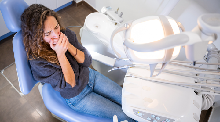 Person covering their mouth at the dentist.