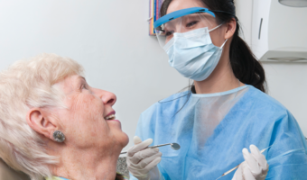 Dentist performing an oral health exam on an older adult.